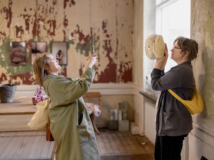 Sofi Svensson håller upp ett keramik-huvud som Amalia Bille ställer ut. Foto: Nora Lorek.